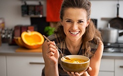 A smiling woman holding a bowl of soup