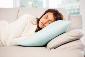 Woman sleeping on couch with head raised with pillows